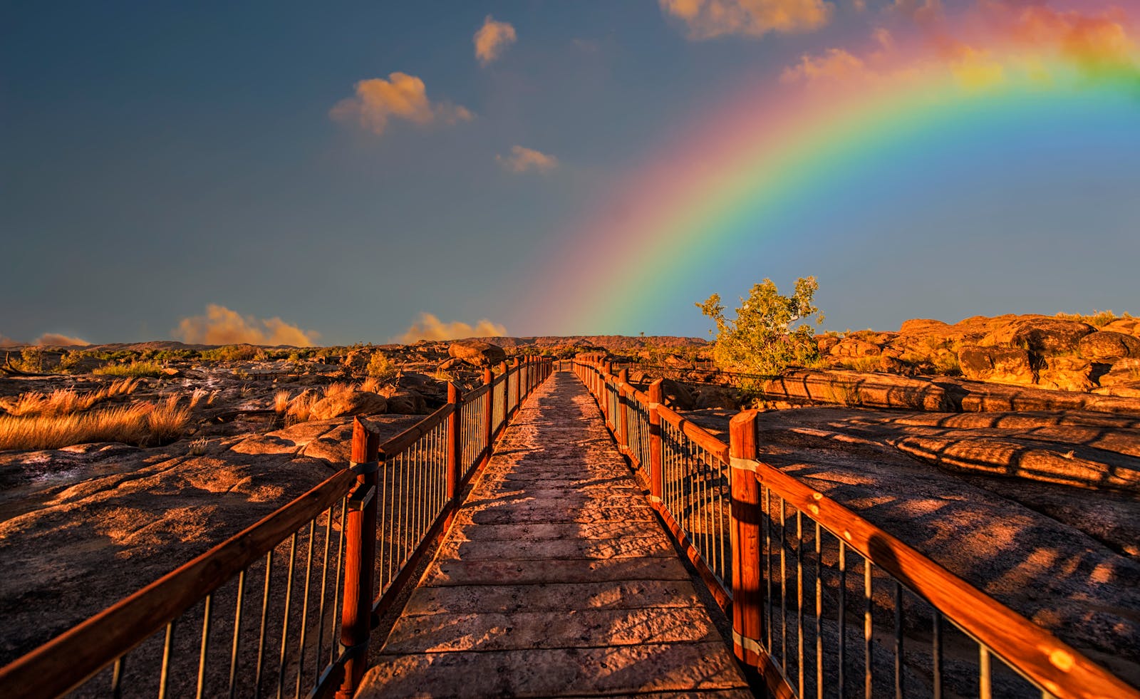 A scenic walkway with a rainbow arching across a vivid sky, perfect for outdoor photography.
