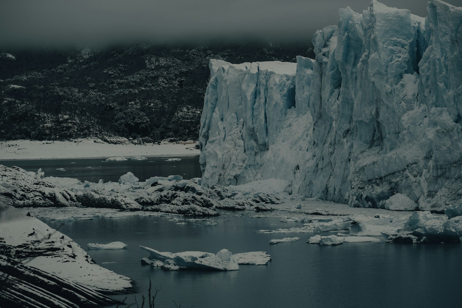 a body of water with ice and snow on the side