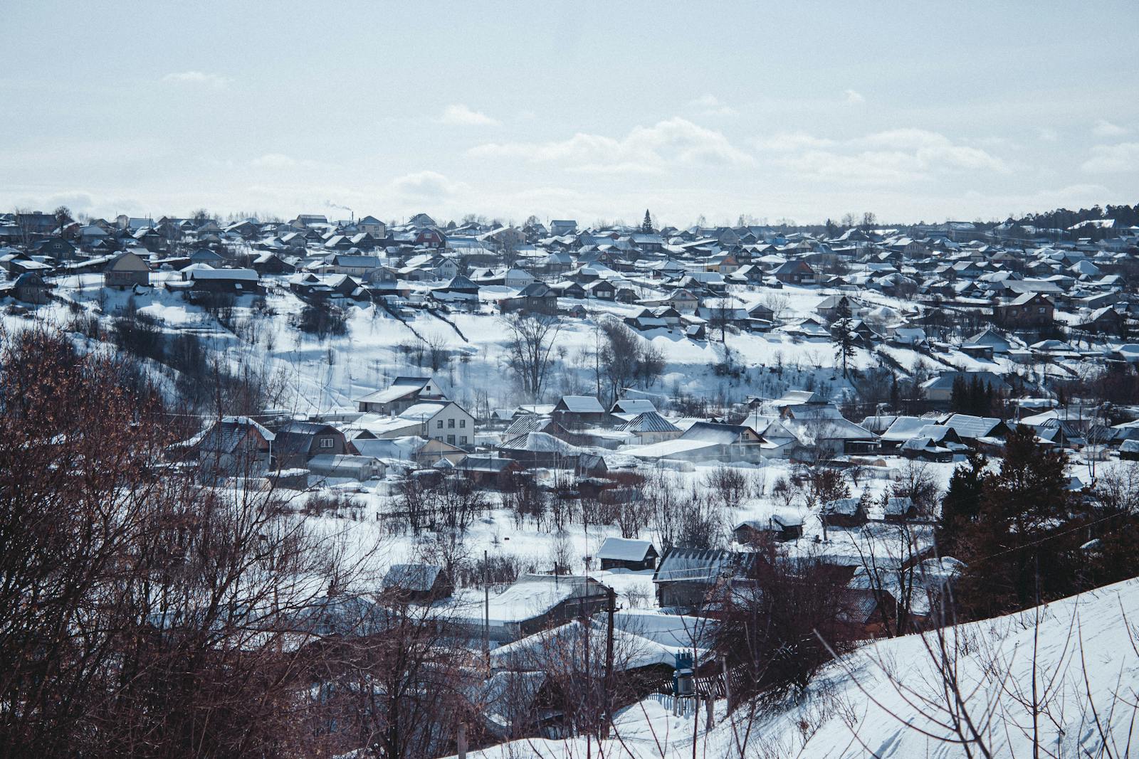 A serene snowy village landscape under a clear blue sky, showcasing winter beauty.